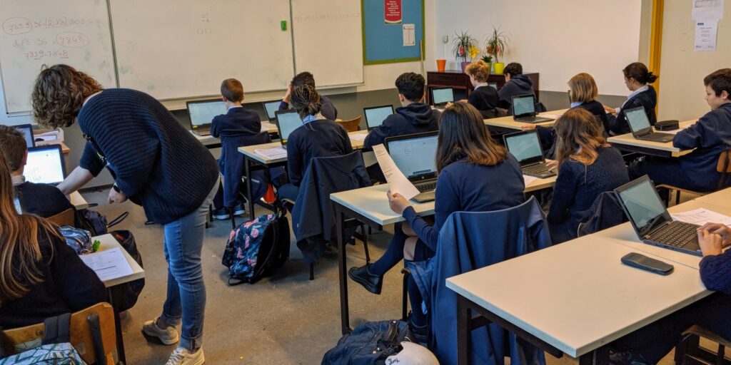 Een klas met leerlingen die op een laptop werken